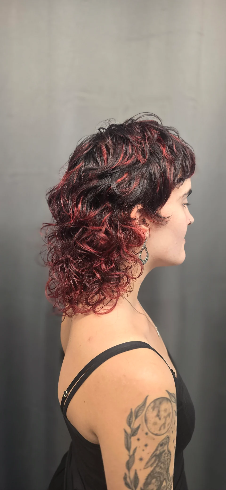 Curly short hair with burgundy tones and a dark fringe